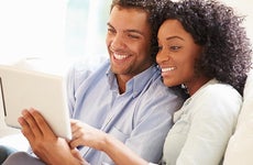 Couple sitting on white couch, browsing tablet computer | Monkey Business Images/Shutterstock.com