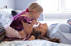 Mature lady and young girl playing in the bedroom | Jon Ragel/Getty Images