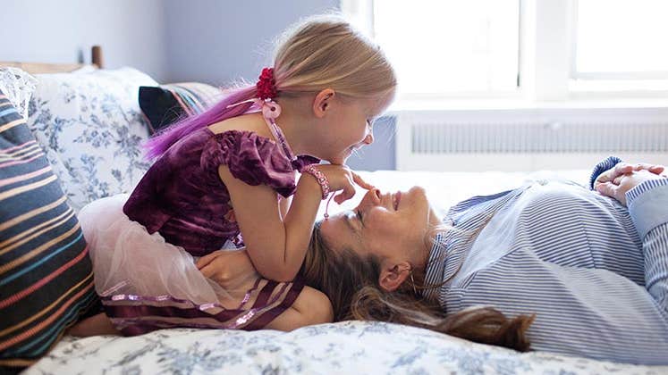 Mature lady and young girl playing in the bedroom | Jon Ragel/Getty Images