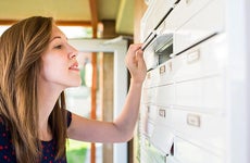 Woman checking her apartment mailbox | l i g h t p o e t/Shutterstock.com