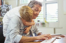 Young son hugging dad working from home office | Paul Bradbury/Getty Images