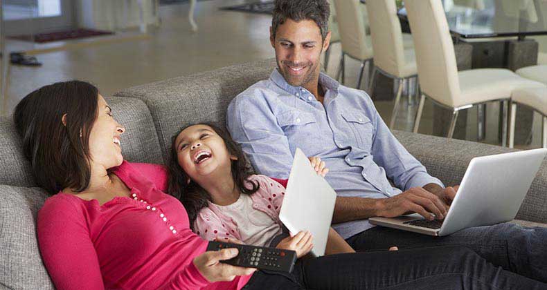 Family with their devices sitting together on couch | Monkey Business Images/Shutterstock.com