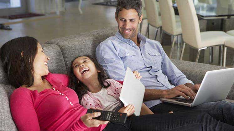 Family with their devices sitting together on couch | Monkey Business Images/Shutterstock.com