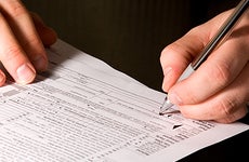Man signing tax form © Mehmet Dilsiz - Fotolia.com