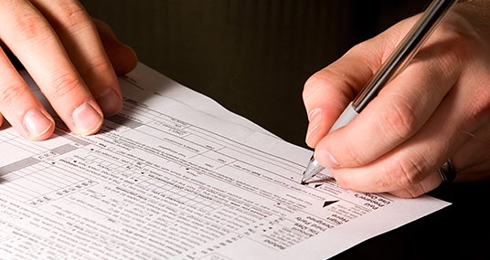 Man signing tax form © Mehmet Dilsiz - Fotolia.com