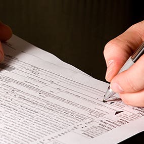 Man signing tax form © Mehmet Dilsiz - Fotolia.com