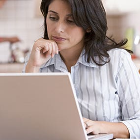 Woman in the kitchen using a laptop with man in the background © Monkey Business - Fotolia.com