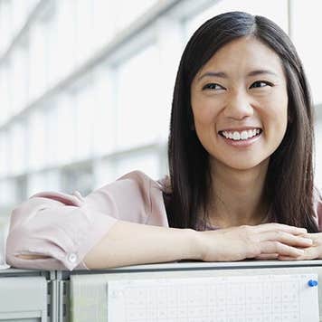 Smiling young woman in work office | Hero Images/Getty Images