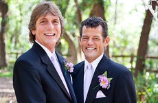 Gay couple getting married under a floral archway © Lisa F. Young/Shutterstock.com