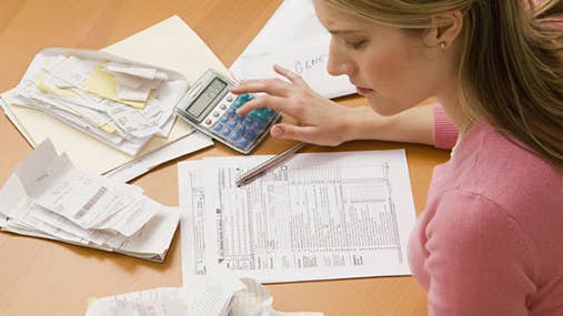 Young blond woman in pink shirt doing taxes © micro10x/Shutterstock.com