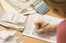 Young woman fills out tax form with receipts © micro10x/Shutterstock.com