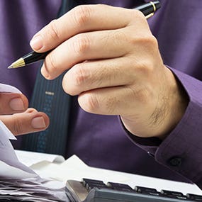 Man working on finances © patpitchaya/Shutterstock.com