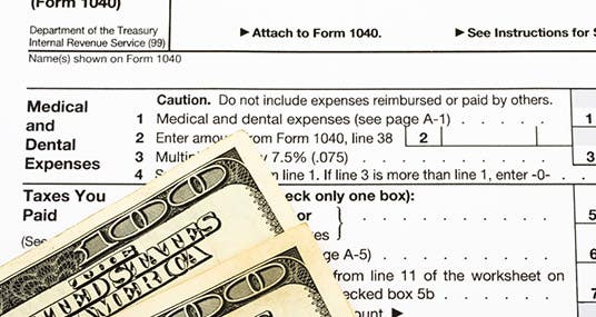 Hundred dollar bills sitting on federal tax forms © karen roach/Shutterstock.com