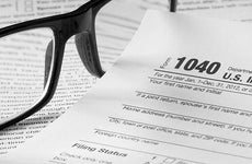 Form 1040 with glasses and pen © topseller/Shutterstock.com
