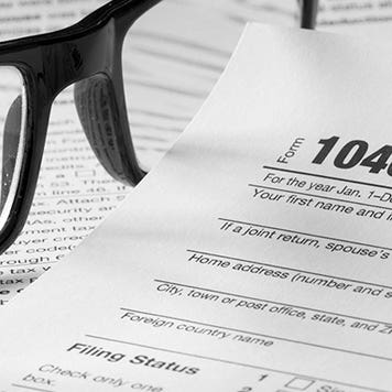 Form 1040 with glasses and pen © topseller/Shutterstock.com