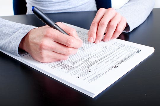 Male hand filling out tax form © kurhan/Shutterstock.com