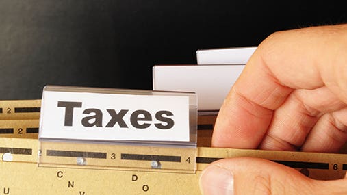 Male hand holding folder with tab labeled &quot;Taxes&quot; © gunnar3000 - Fotolia.com
