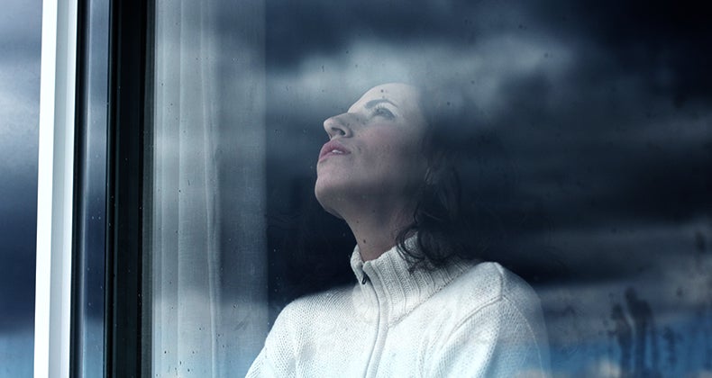 Sad woman looking through the window © Dubova/Shutterstock.com