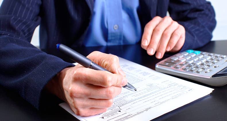 Man in blue jacket filling up tax return form © docent/Shutterstock.com