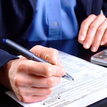 Man in blue jacket filling up tax return form © docent/Shutterstock.com