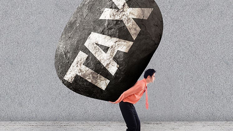 Stressed man carring a big rock of tax on his back © Creativa Images/Shutterstock.com