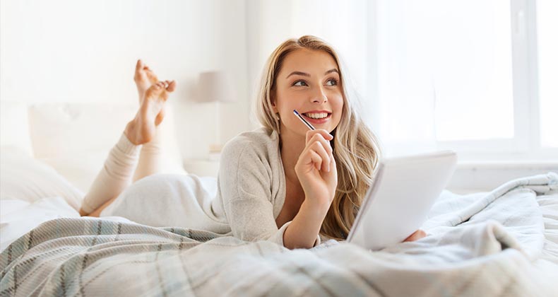 Woman writing notes on bed | Syda Productions/Shutterstock.com