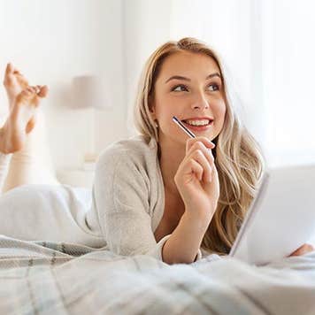Woman writing notes on bed | Syda Productions/Shutterstock.com