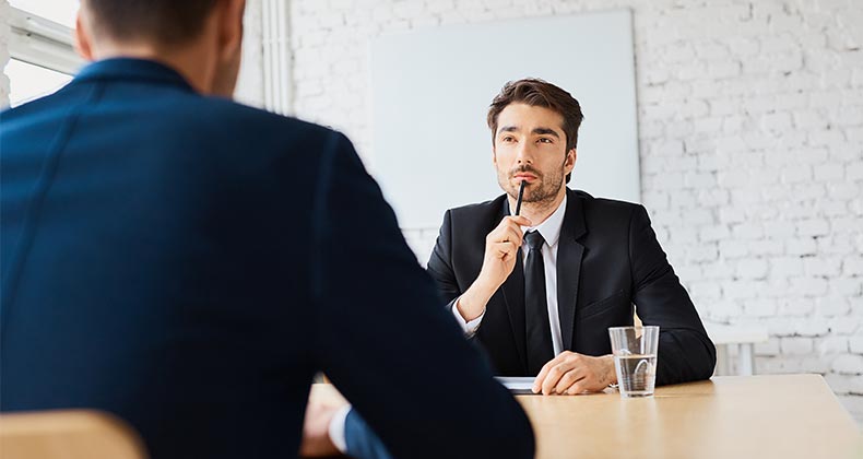 Man in suit, thinking during an interview | baranq/Shutterstock.com