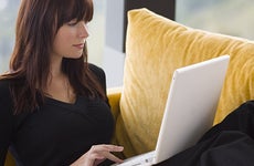 Brunette woman in black top using laptop at home © Darren Baker - Fotolia.com