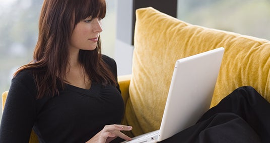 Brunette woman in black top using laptop at home © Darren Baker - Fotolia.com