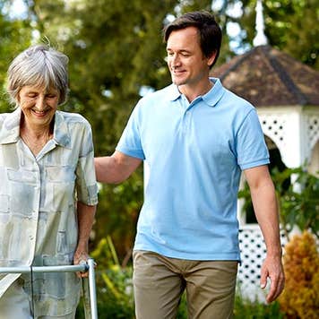 Adult son walking with senior parent in a walker | Morsa Images/Getty Images