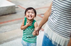 Smiling child holding mother's hand | Images By Tang Ming Tung/Getty Images