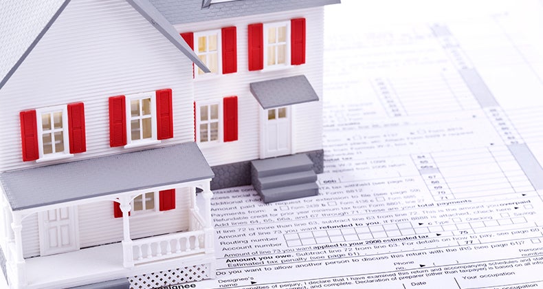 Toy house on top of 'Sign here' section of tax form © iStock