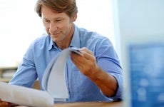 Smiling middle aged man reading paperwork © iStock