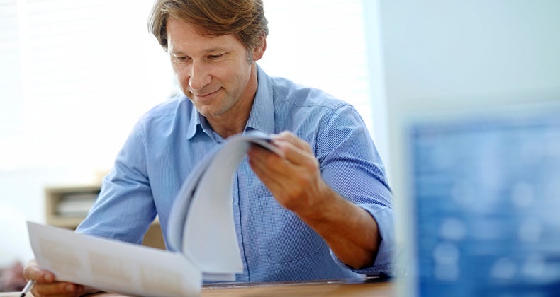 Smiling middle aged man reading paperwork © iStock