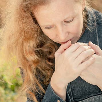 Sad woman sitting outside on a cement wall © altanaka/Shutterstock.com