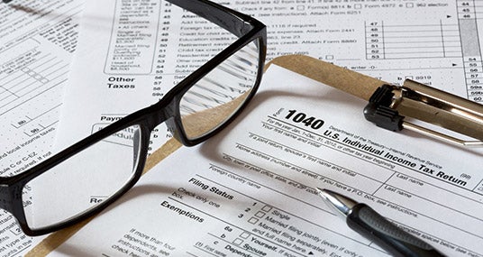 Tax forms on clipboard with glasses and pen © topseller/Shutterstock.com