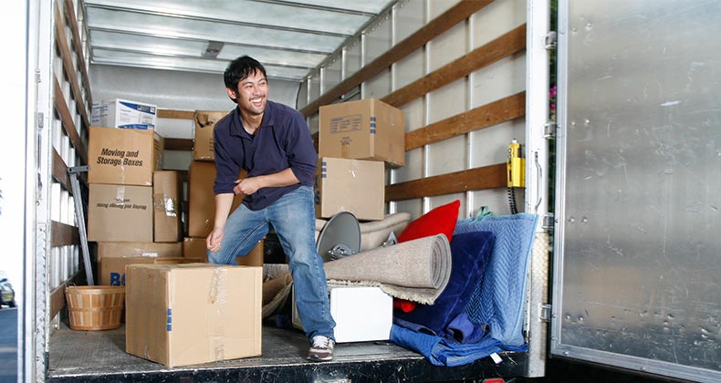 Man happily unloading boxes from boxtruck | John Eder/Getty Images