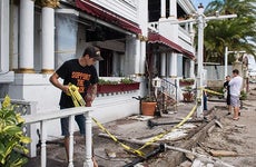 Man removing yellow caution tape from damaged home | The Washington Post/Getty Images