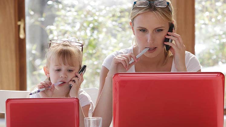 Mom and daughter browsing matching laptops | Peter Cade/Getty Images