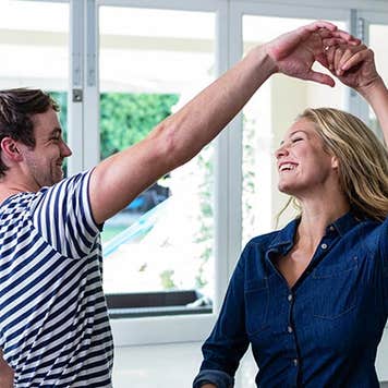 Young couple laughing and dancing together in kitchen | wavebreakmedia/Shutterstock.com