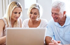 Adult daughter showing computer screen to senior parents © iStock