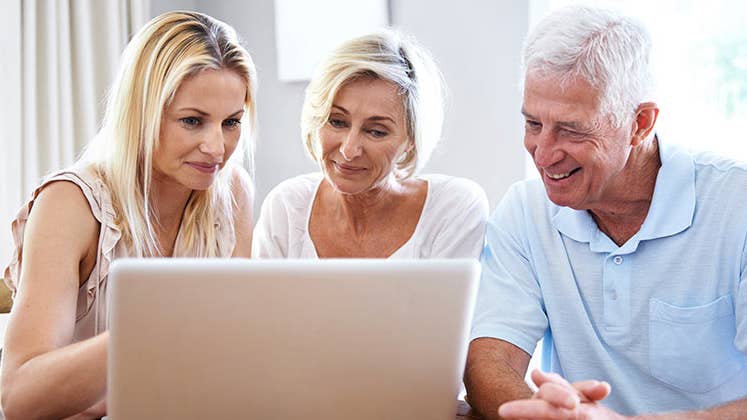 Adult daughter showing computer screen to senior parents © iStock