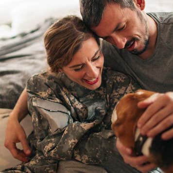A couple petting their dog | AleksandarNakic/E+/Getty Images
