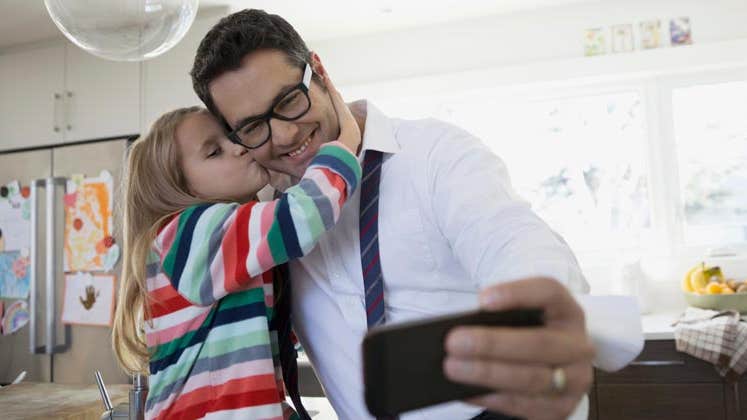 Father taking a selfie with his daughter | Hero Images/Getty Images