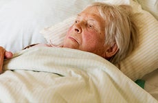 Elderly woman laying on bed | SilviaJansen/E+/Getty Images