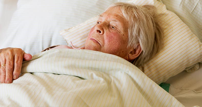 Elderly woman laying on bed | SilviaJansen/E+/Getty Images