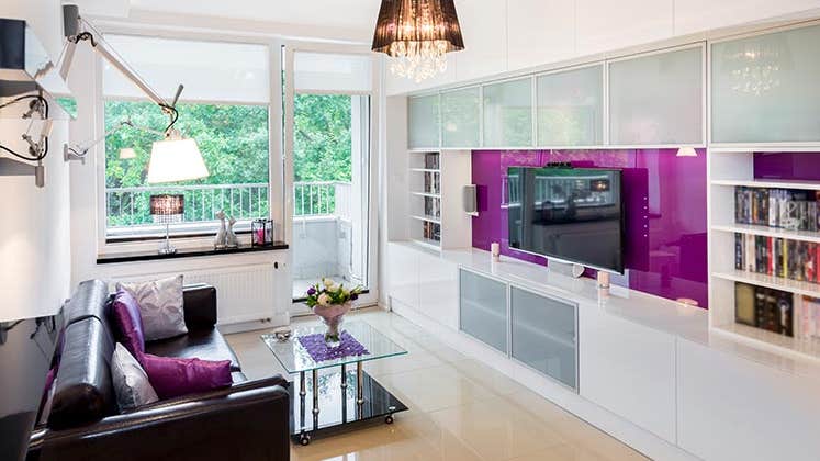 Modern apartment living room with purple TV wall | Jacek Kadaj/Getty Images