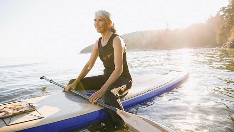 Senior woman sitting on kayak | Hero Images/Getty Images
