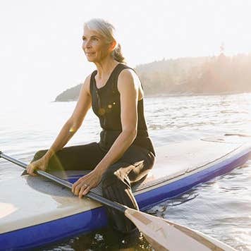 Senior woman sitting on kayak | Hero Images/Getty Images